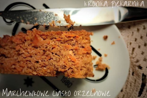 Kawałek wilgotnego ciasta z marchewką i orzechami obok noża