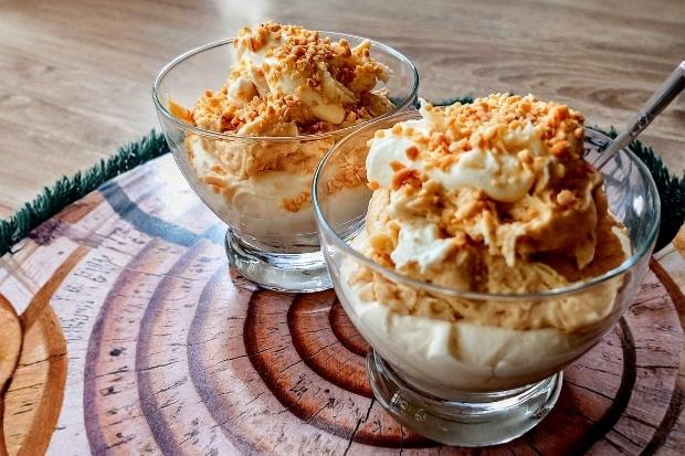 Kremowe keto lody karmelowe posypane orzeszkami na drewnianym blacie